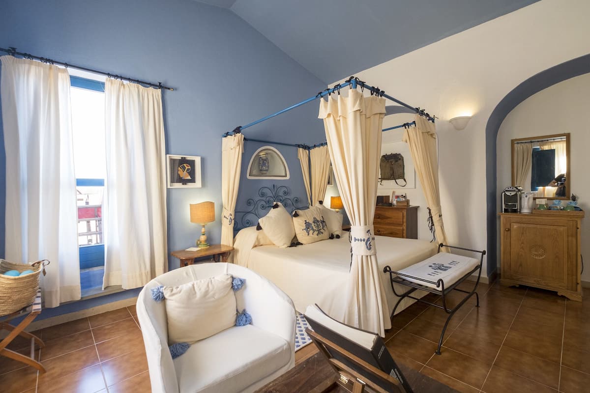 Une chambre à coucher avec un lit à baldaquin, une table de chevet avec une lampe, une armoire en bois et une chaise.