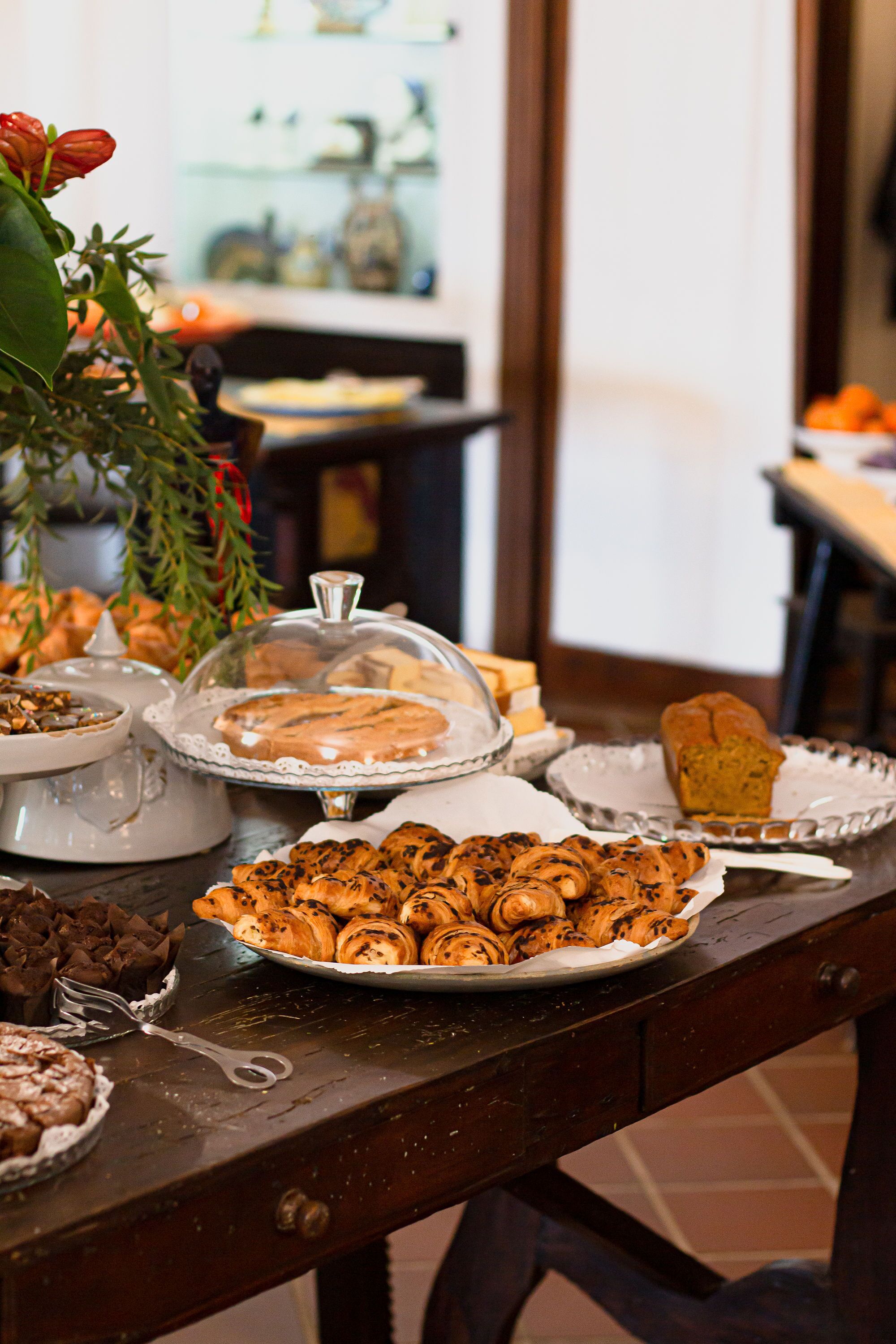 Une table garnie de diverses pâtisseries et de desserts, notamment un gâteau recouvert d’un couvercle et une assiette de muffins.