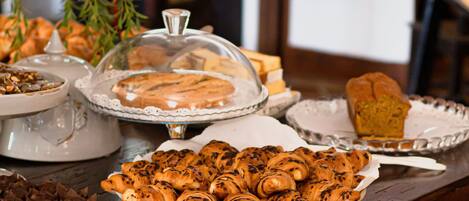 Une table garnie de diverses pâtisseries et de desserts, notamment un gâteau recouvert d’un couvercle et une assiette de muffins.