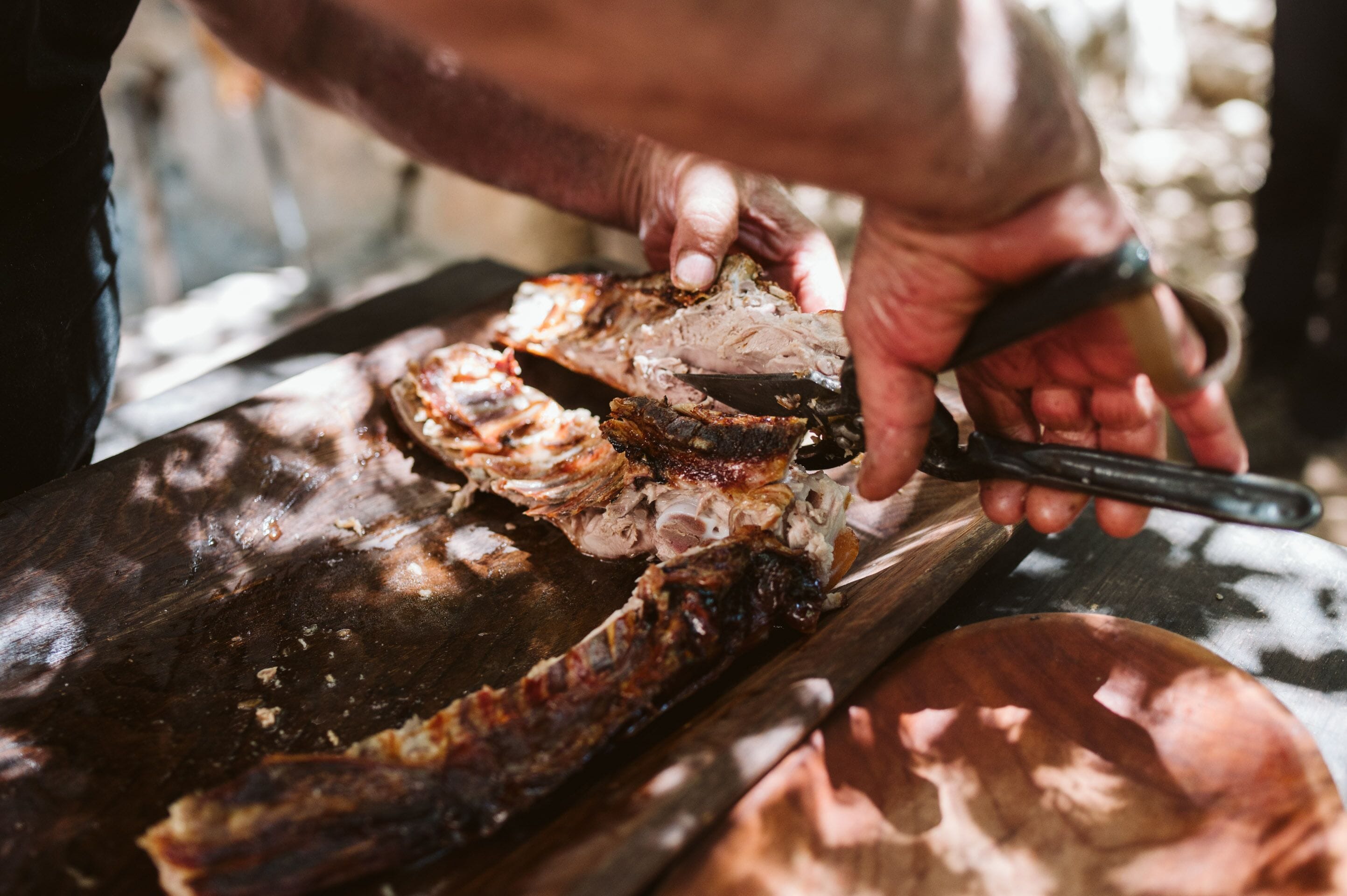 A person carving meat on a wooden cutting board.