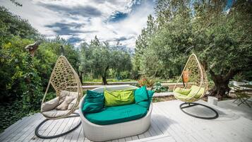 A deck with a circular seating area featuring two hanging chairs and a cushioned bench.