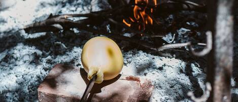 A charcoal grill with a single apple roasting over the flames.