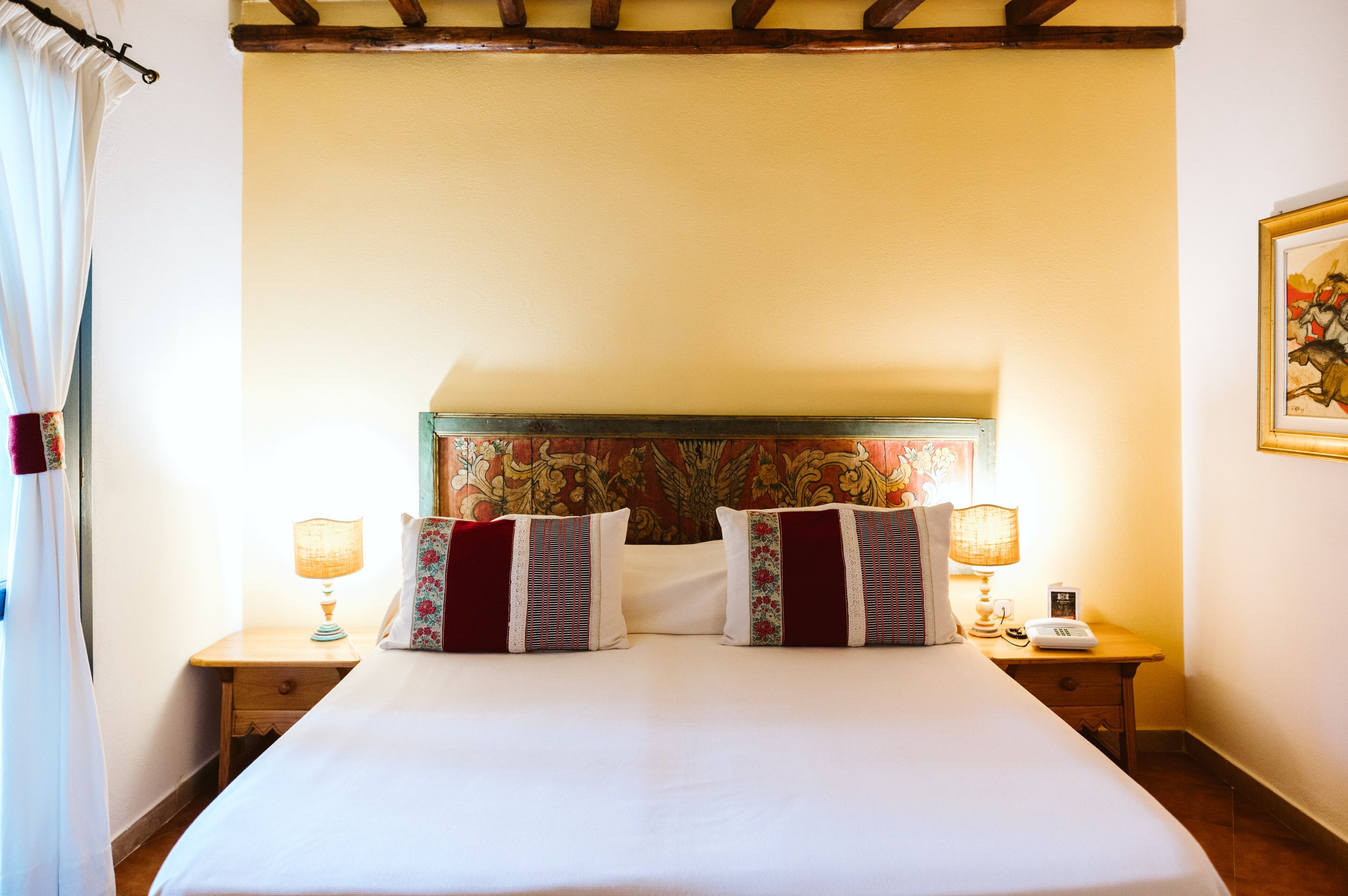 A neatly made bed with floral headboard and two bedside lamps.