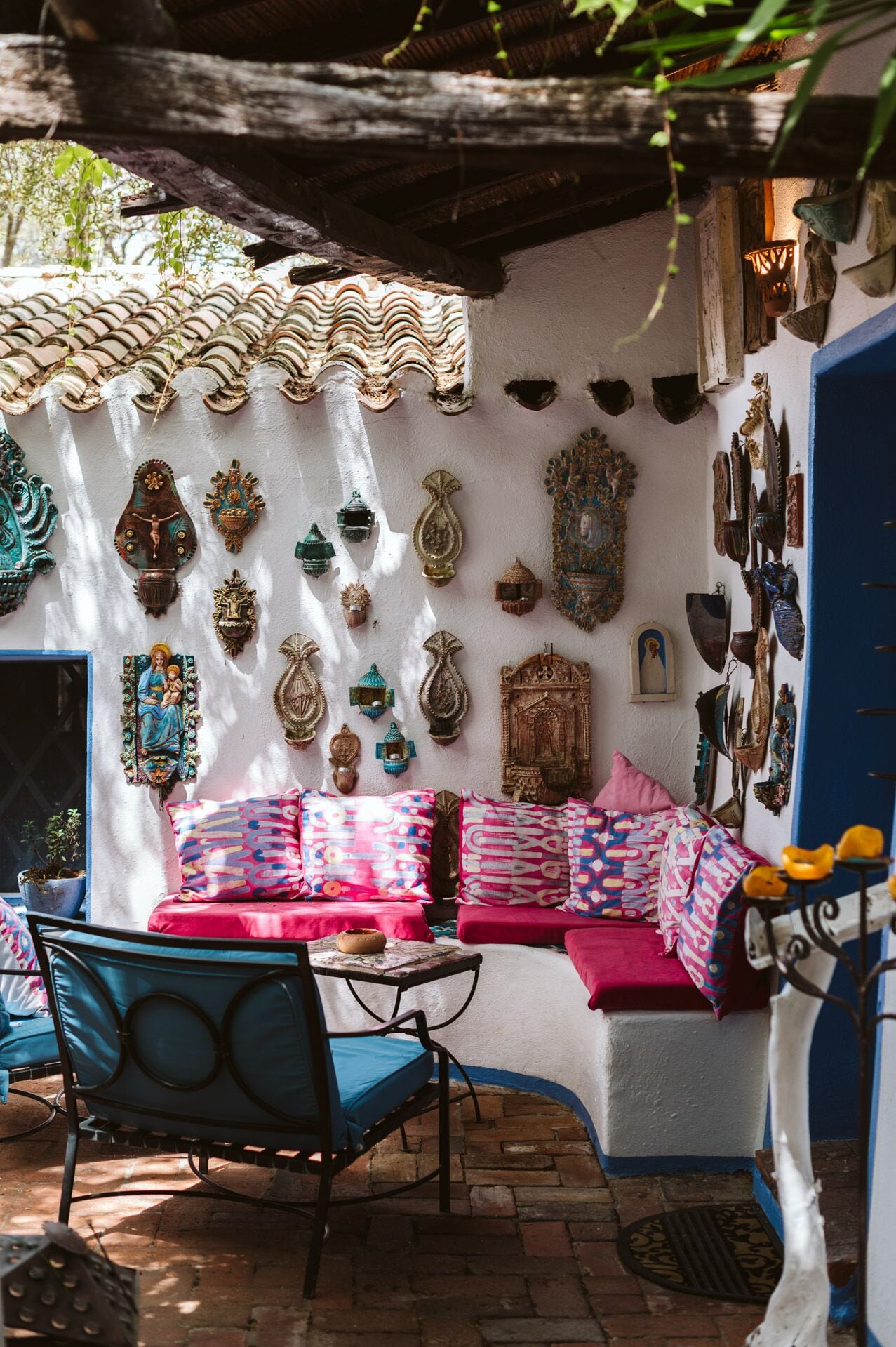 Un espacio al aire libre acogedor con un banco acolchado, una mesa de metal y una silla.