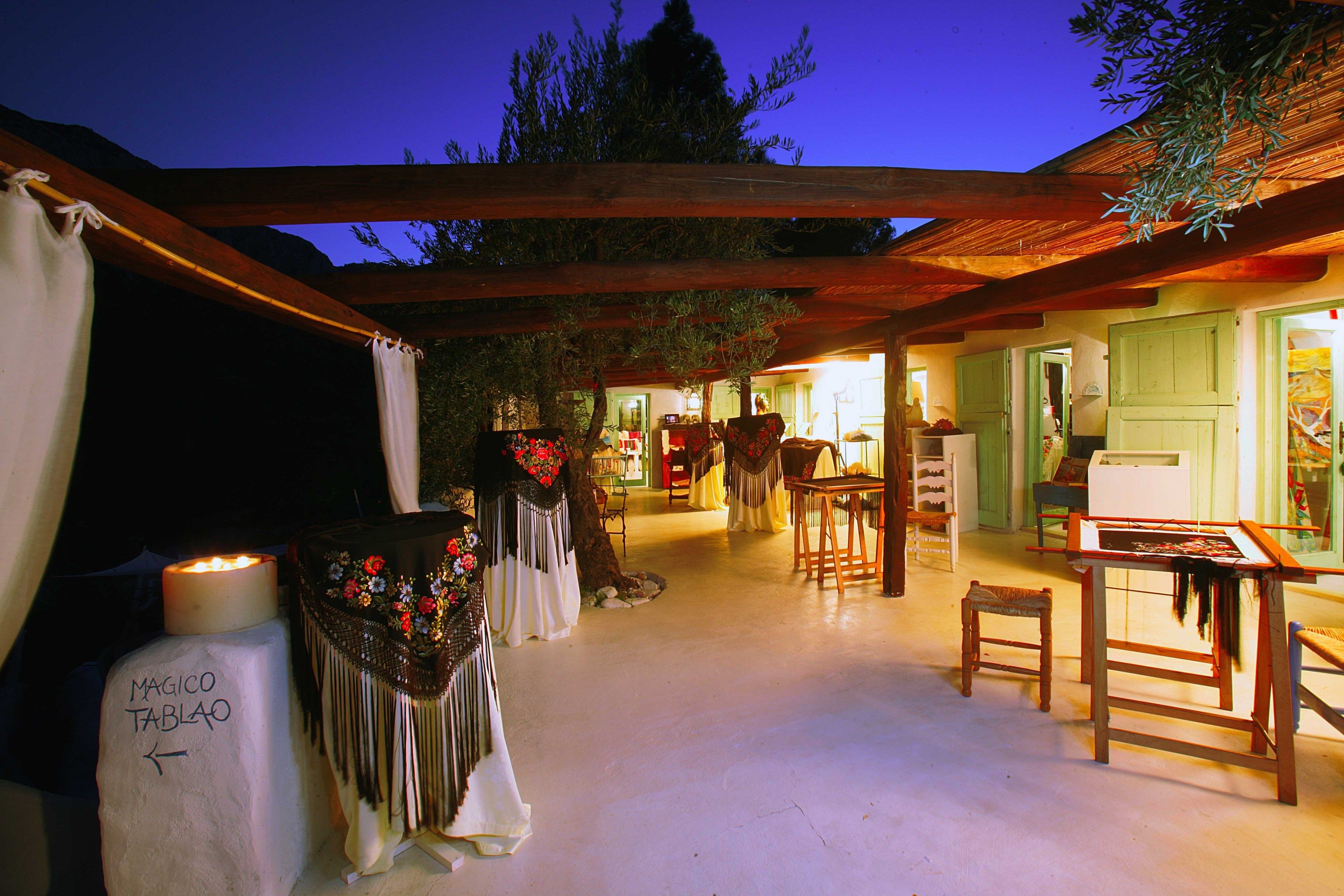 Una zona de estar exterior acogedora con mobiliario de madera y una mesa, rodeada por una pérgola de madera.