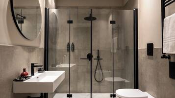 Une salle de bain moderne avec une douche à parois de verre, un lavabo blanc et des toilettes.