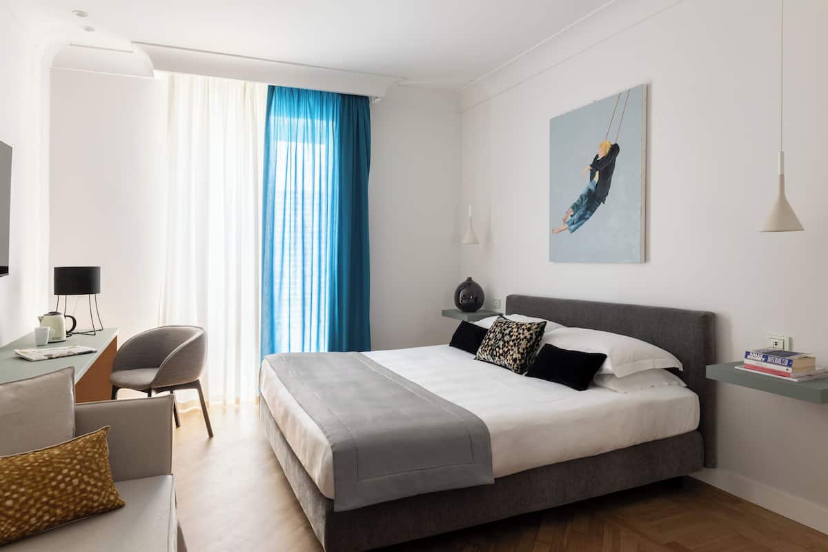 A modern hotel room with a large bed, a desk, and a chair.