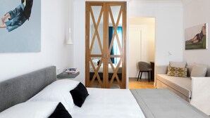 Een moderne hotelkamer met een groot bed, een bureau, een bank en een houten roomdivider.