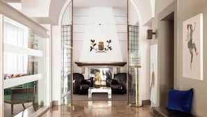 Een ruime woonkamer met een hoge plafond, een open haard en een uitzicht door een boog naar een balkon.