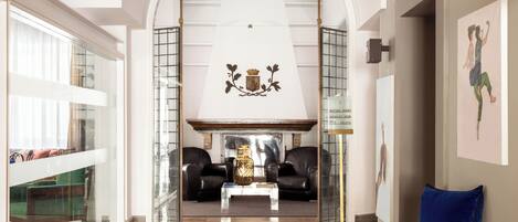 A spacious living area with a high ceiling, a fireplace, and a view through an archway to a balcony.