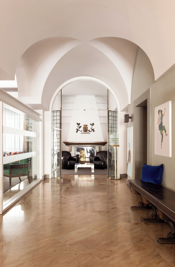 A spacious living area with a high ceiling, a fireplace, and a view through an archway to a balcony.