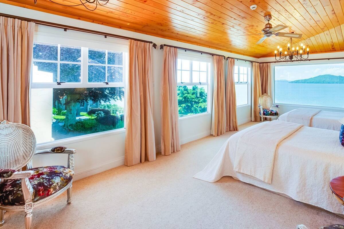 Un dormitorio con una cama grande, ventilador de techo y vista a un cuerpo de agua.