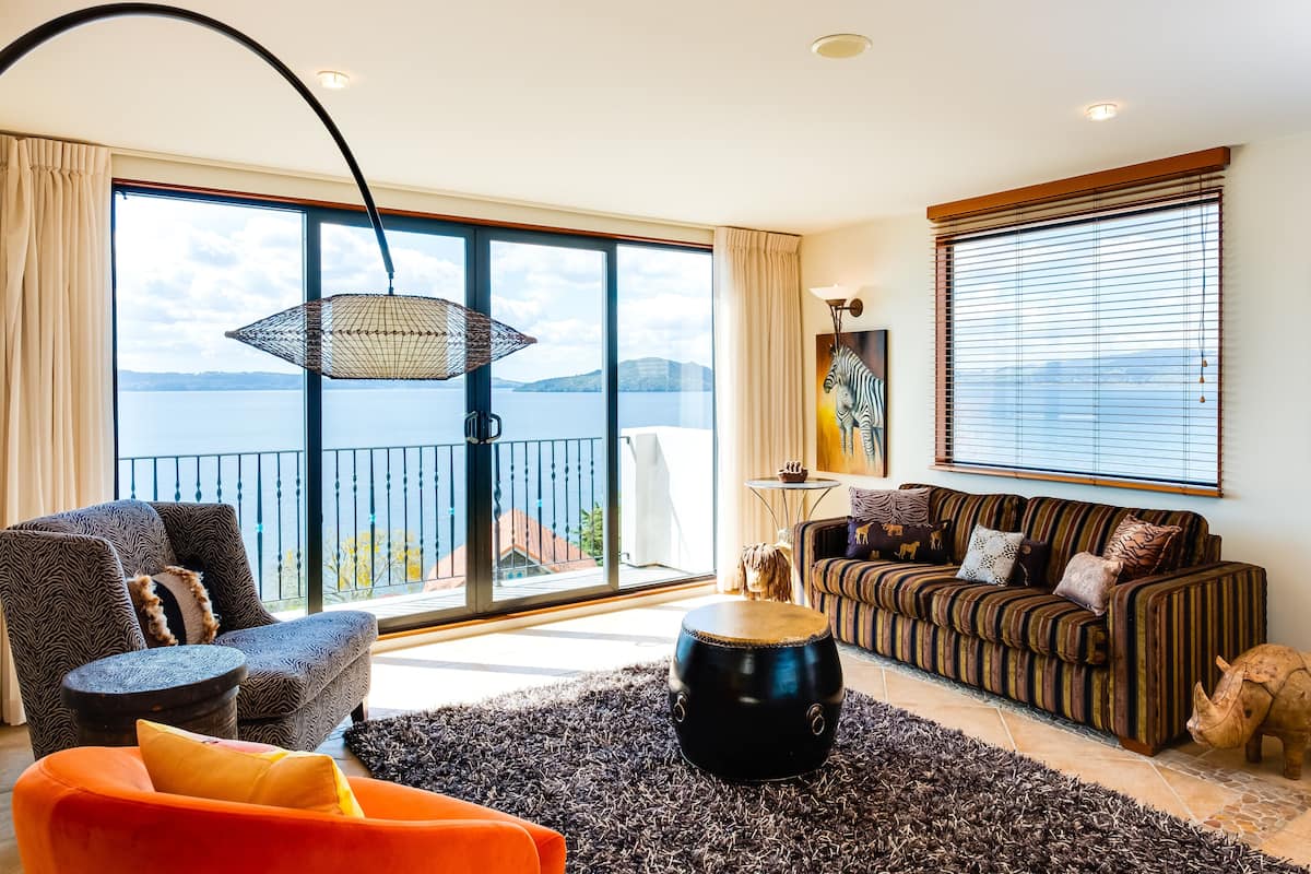 Un salón espacioso con un ventanal que ofrece vistas al mar, un cuadro de cebra y un sofá a rayas.