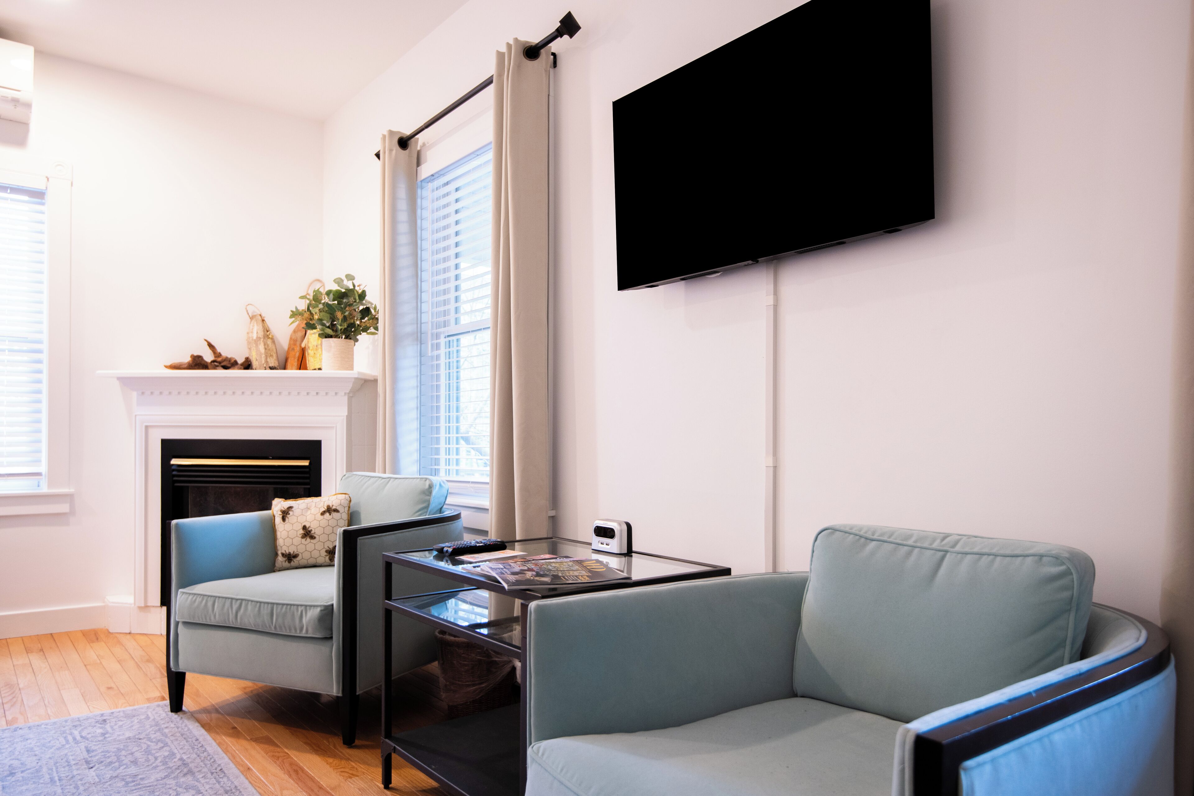 A modern living room with a fireplace, two sofas, a flat-screen TV, and a glass coffee table.