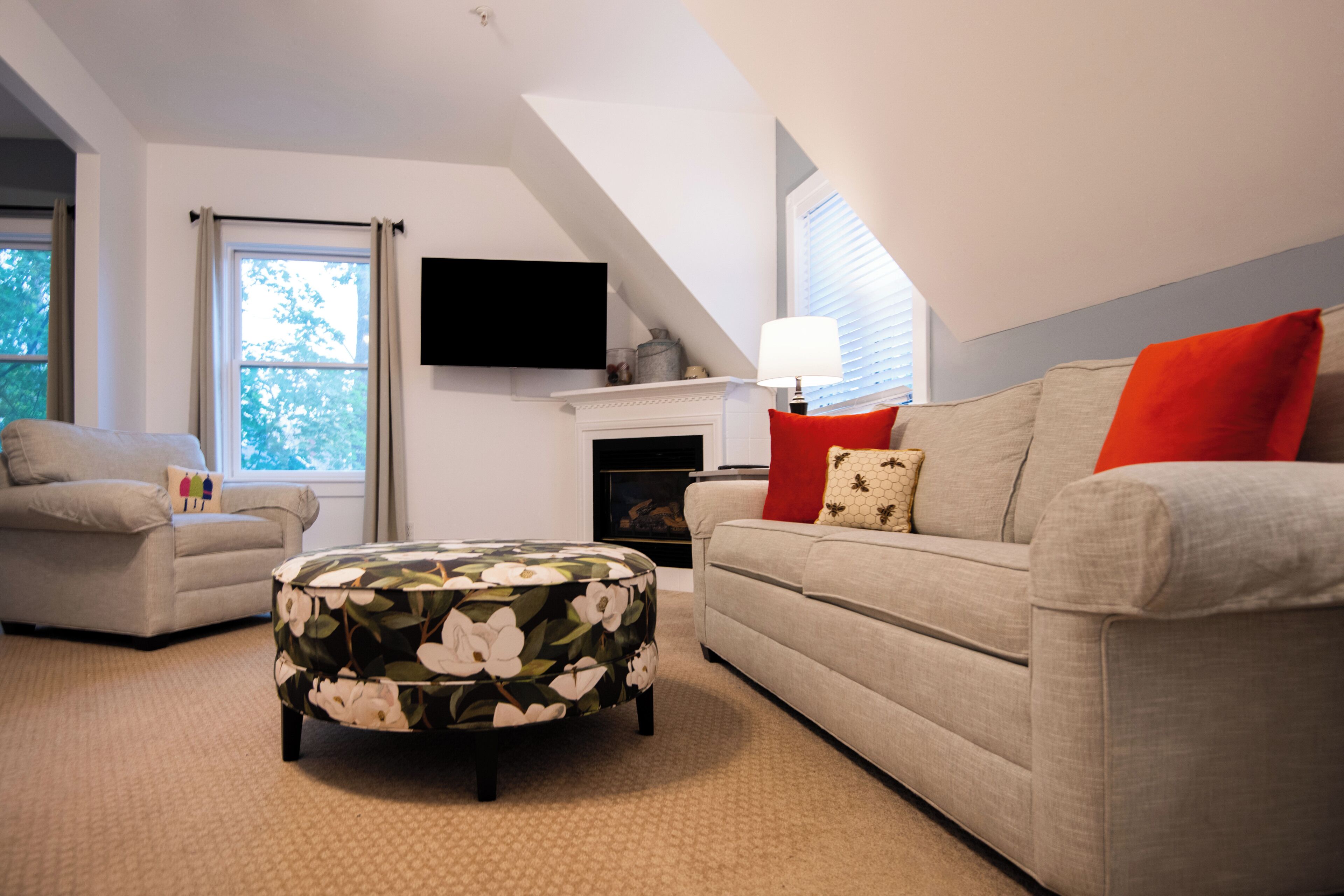 Ein Wohnzimmer mit Sofa, Hocker und Kamin.
