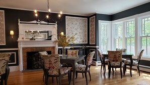 Un coin repas agrémenté d’une cheminée, de parquet et de chaises à motifs.