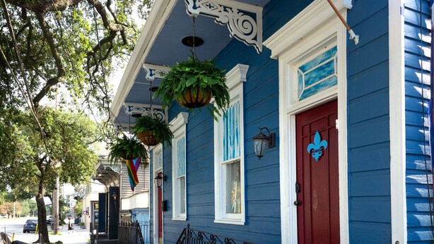 A blue building with a red door, white trim, and hanging plants. - Blue60 Marigny Inn (New Orleans)