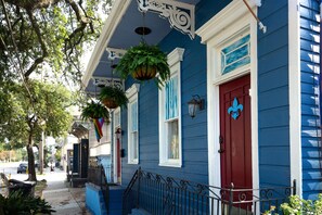 A blue building with a red door, white trim, and hanging plants. - Blue60 Marigny Inn (New Orleans)
