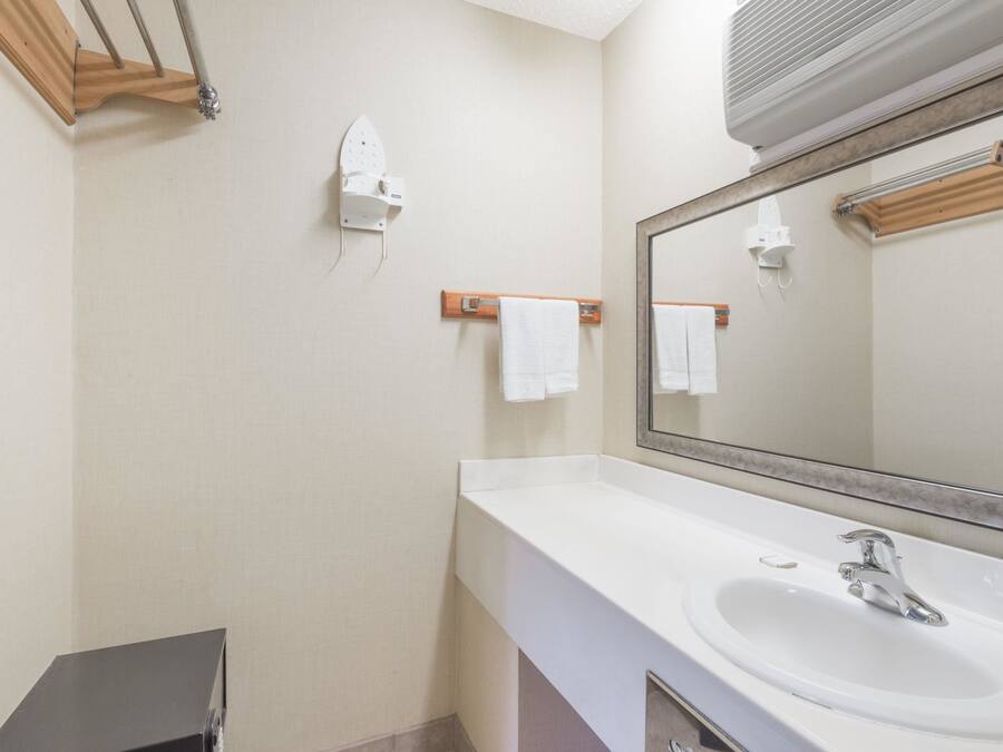 A bathroom with a white sink, a large mirror, and wooden towel racks.