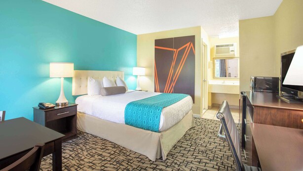 A hotel room with a bed, bedside tables, a desk, and a television.