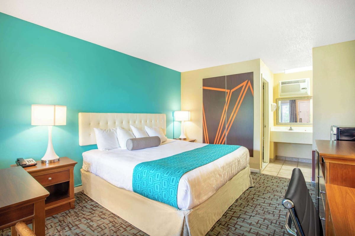 A hotel room with a bed, bedside tables, a desk, and a chair.
