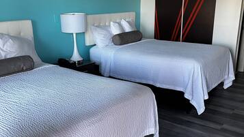 A hotel room with two beds, a nightstand, a lamp, and a wardrobe with a geometric design.