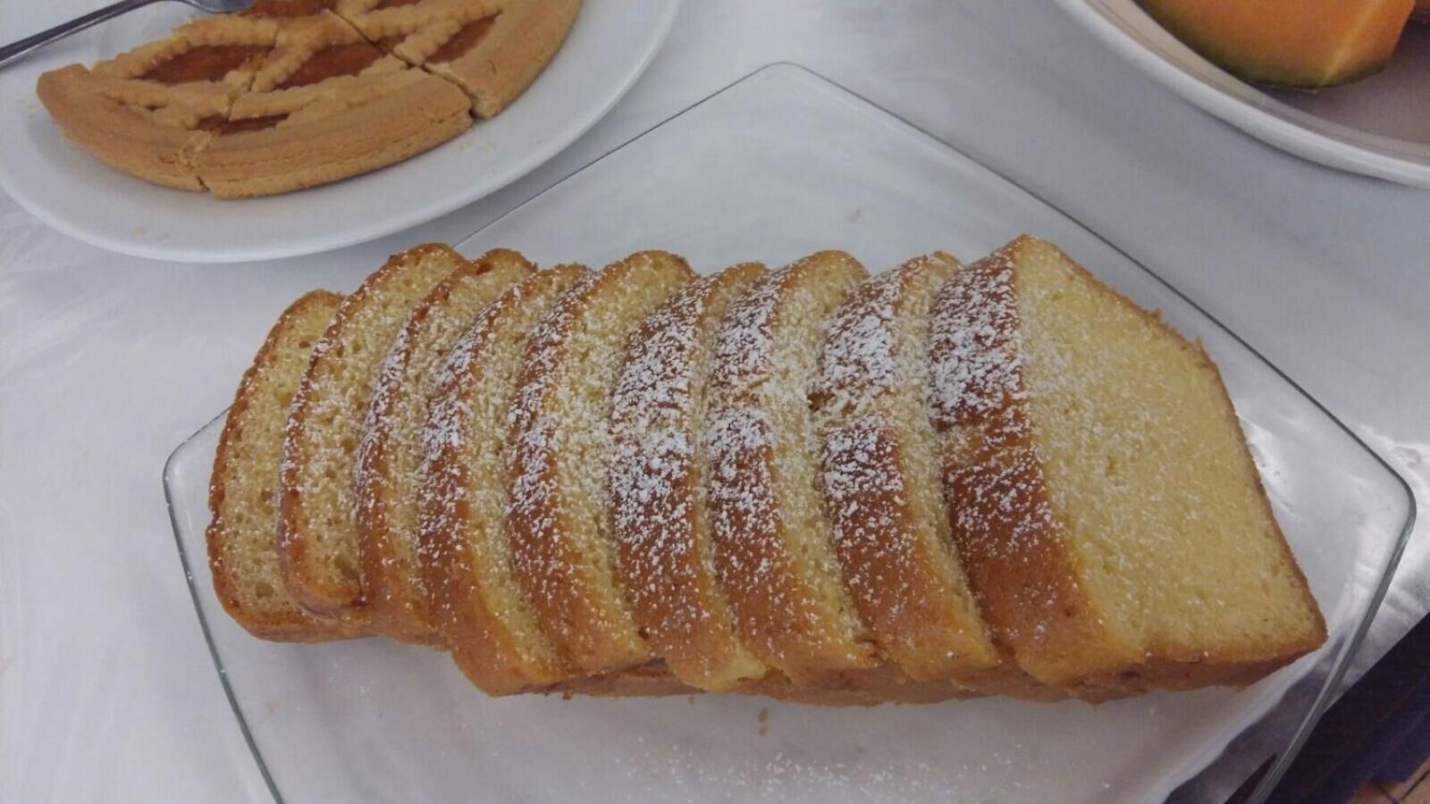 A glass plate with a layered dessert, possibly a cake or pastry, on a white tablecloth.