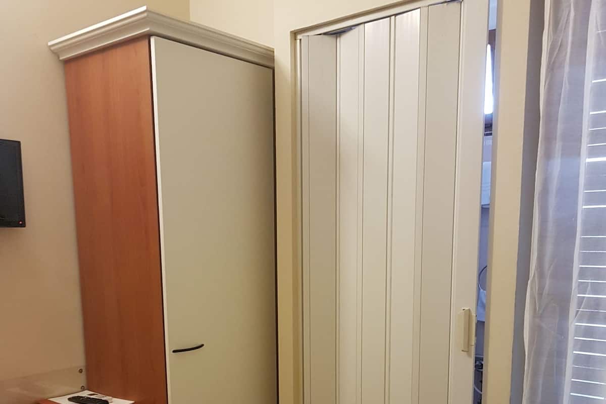 A room with a wooden desk, a wardrobe, and a sliding door.