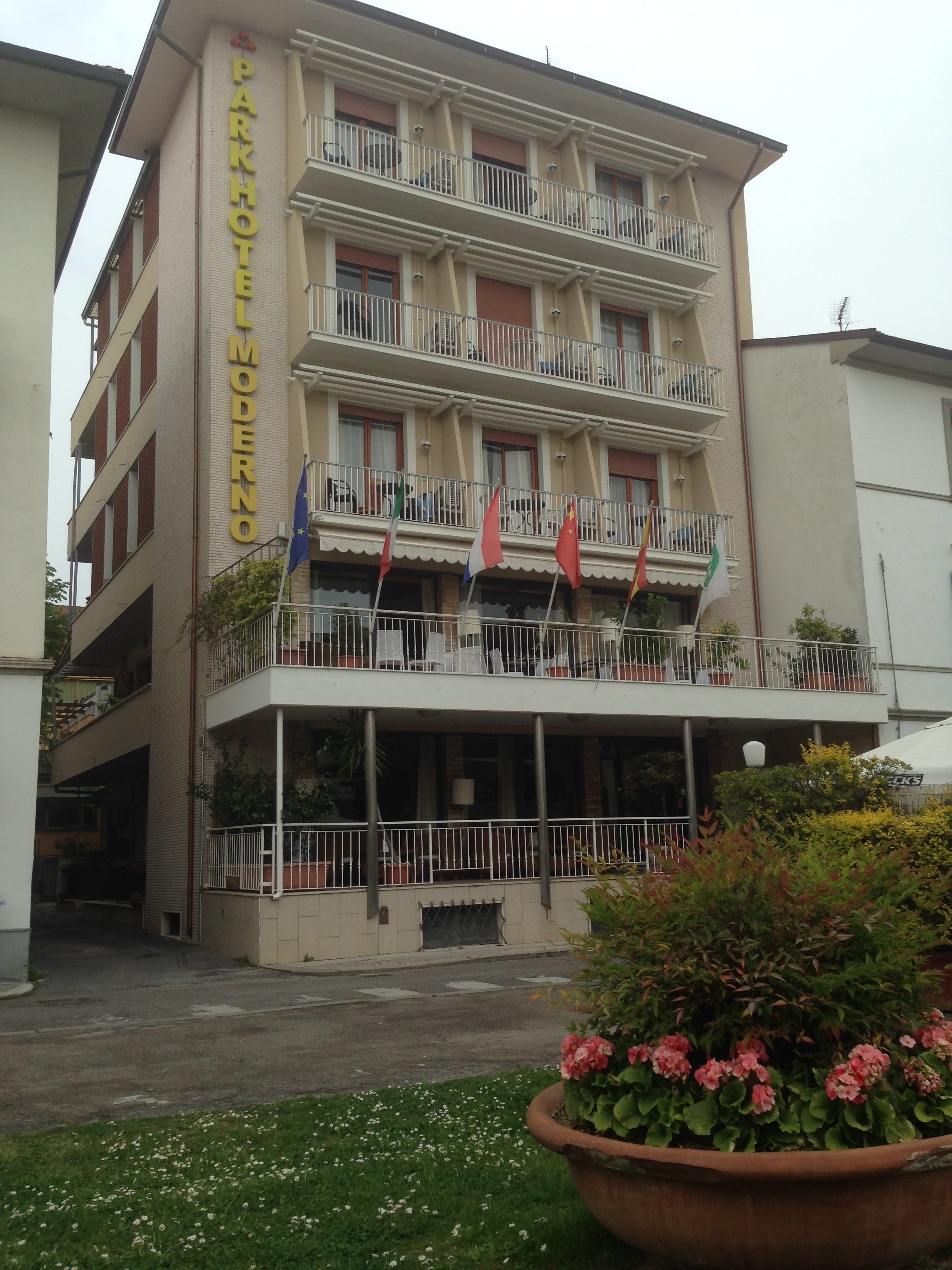 A multi-story hotel with balconies, a sign reading "Parkhotel Moderno", and several flags.