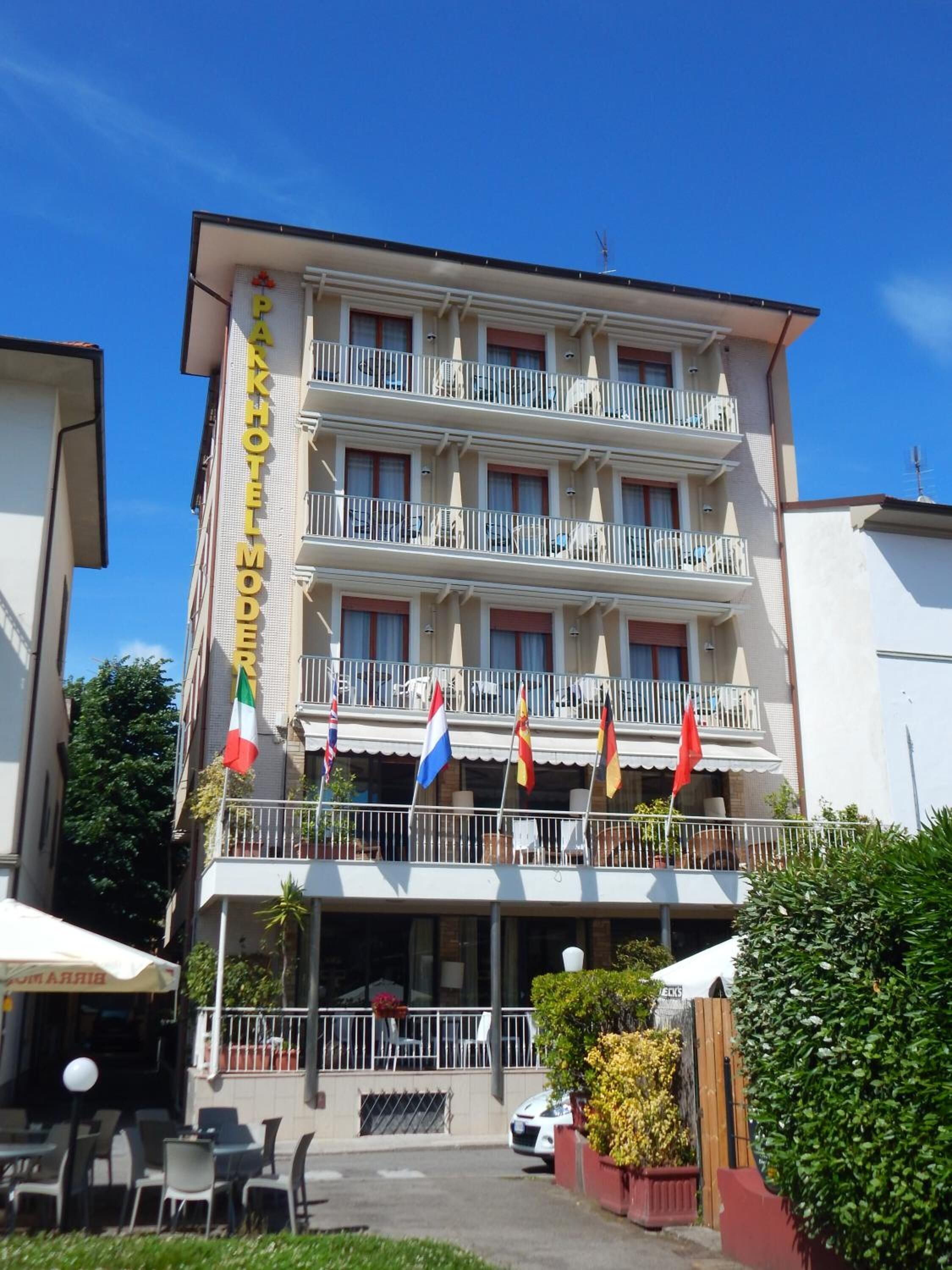 A multi-story hotel with balconies and flags.
