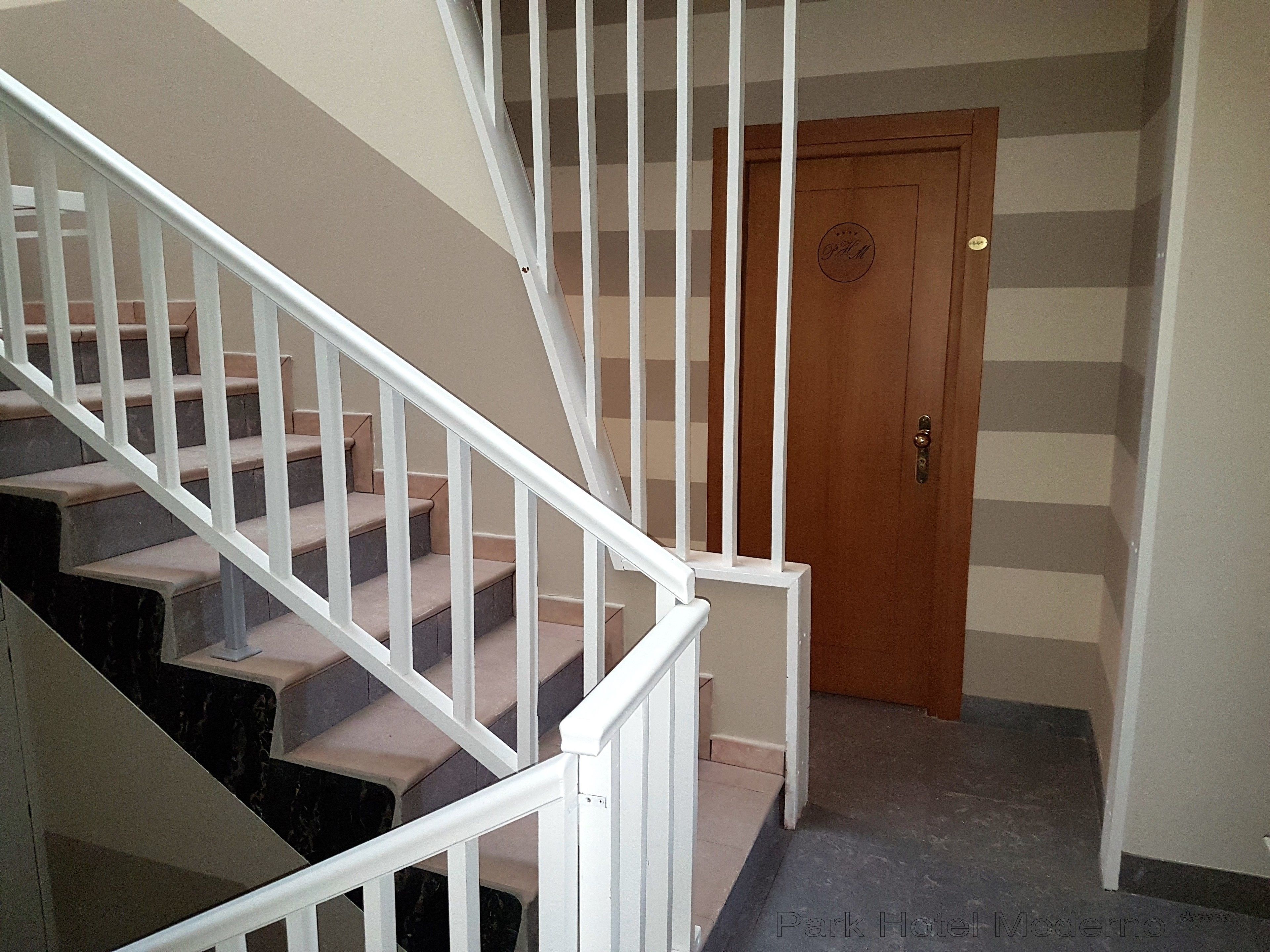 A staircase with white railings leading to a wooden door with a circular emblem.