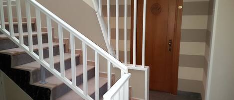 A staircase with white railings leading to a wooden door with a circular emblem.
