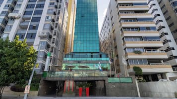 A modern building with a glass facade, surrounded by high-rise residential buildings.