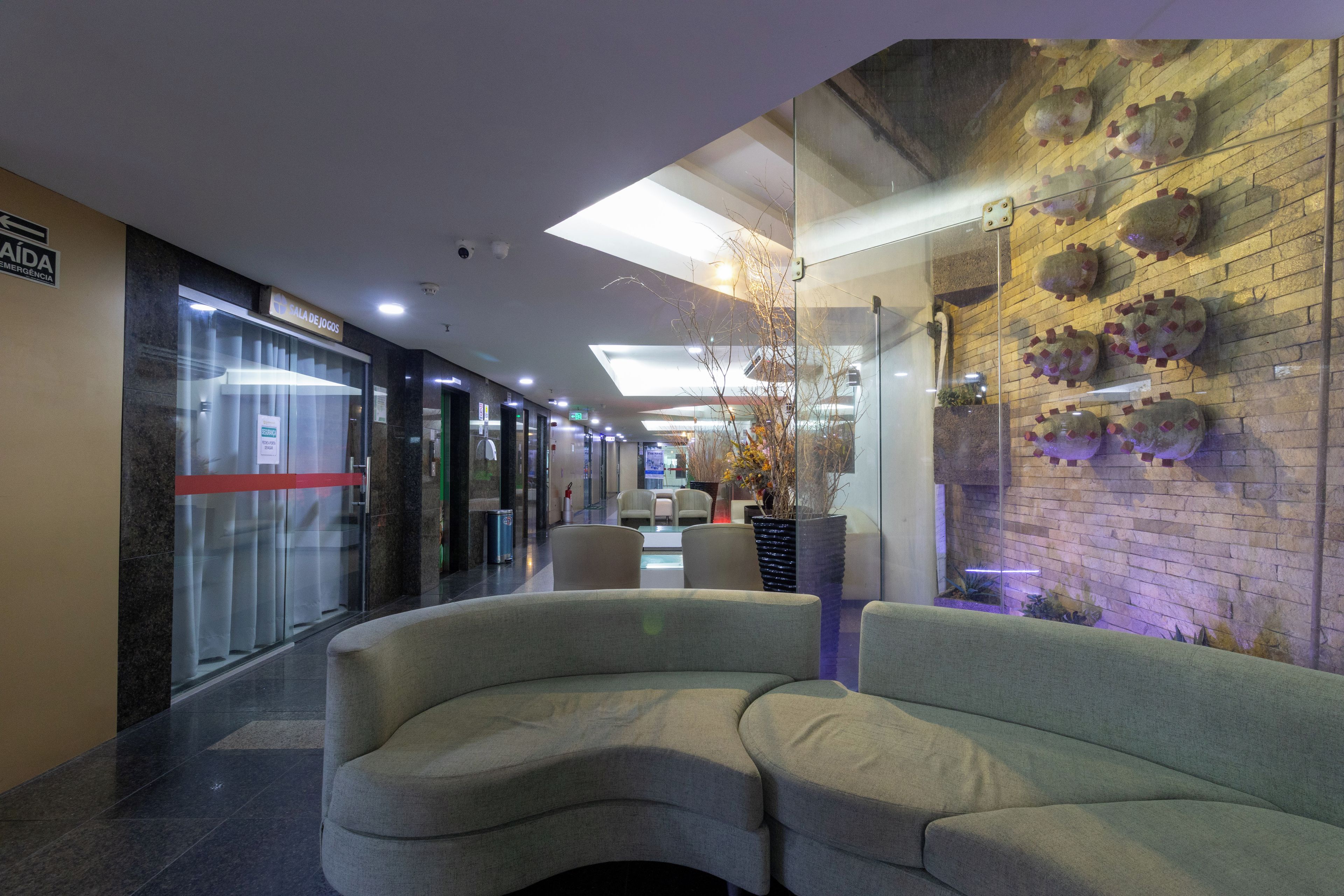 A lobby with a reception desk, seating area, and a wall with decorative elements.