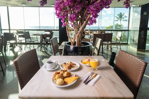 Une table à manger avec des aliments pour le petit-déjeuner, une tasse de café et un verre de jus d’orange.