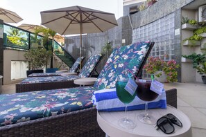 Un espace patio aménagé avec des fauteuils, une table avec des boissons et des plantes en pot.