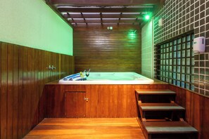 Un interior de madera con bañera de hidromasaje, escalones de madera y un revestimiento de baldosas.