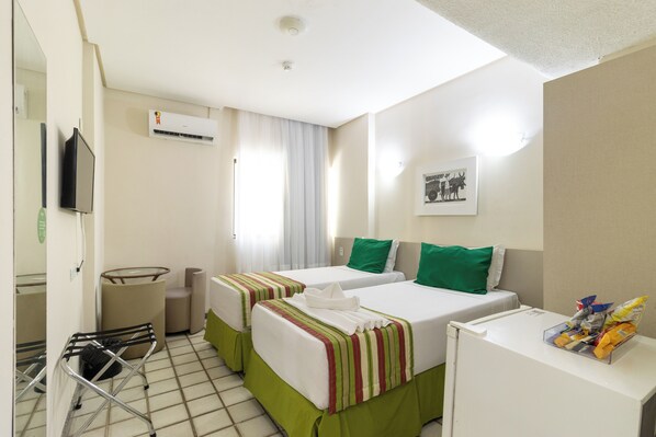 A hotel room with two beds, a TV, an air conditioner, a desk, and a chair.