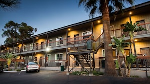A multi-story hotel with balconies, a staircase, and a parking area.
