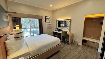 A hotel room with a bed, desk, chair, TV, wardrobe, and a window with a view.