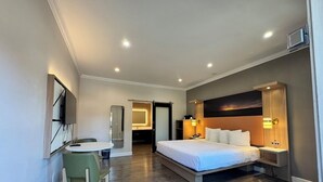 A hotel room with a bed, bedside table, lamp, and a desk with a chair.