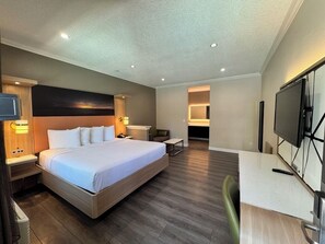 A hotel room with a bed, bedside tables, a TV, a desk, and a chair. - Granada Inn (Granada Hills)
