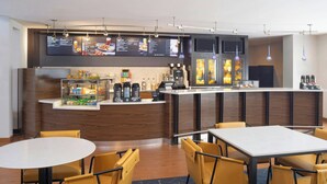 A modern hotel lobby with a reception desk, seating area, and a menu board.
