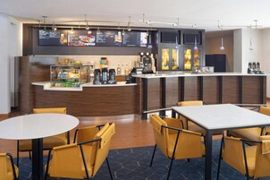Een moderne hotel lobby met een receptiebalie, een zithoek en een menubord.