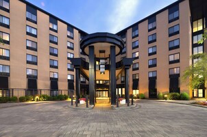 Een hotel met meerdere verdiepingen, een centraal atrium, grote ramen en een aangelegde entree.