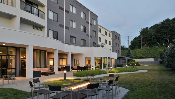 Un hotel amb terrassa exterior, una xemeneia i un jardí ben cuidat.