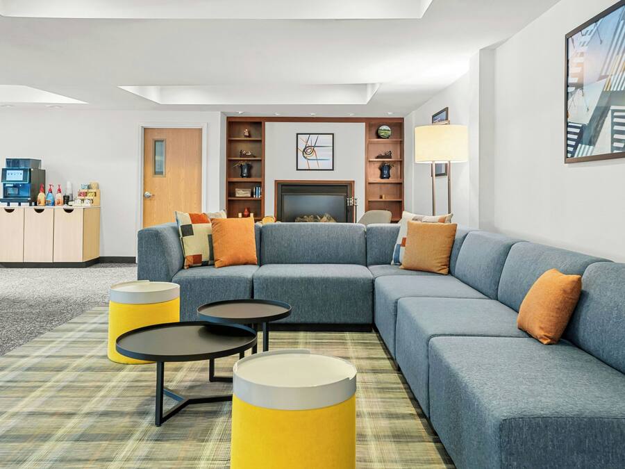 Een moderne woonkamer met een hoekbank, twee kleine ronde tafels en een open haard.