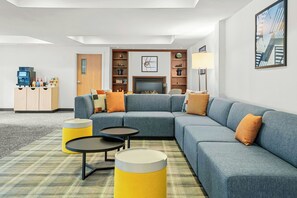 A modern living room with a sectional sofa, two small round tables, and a fireplace.