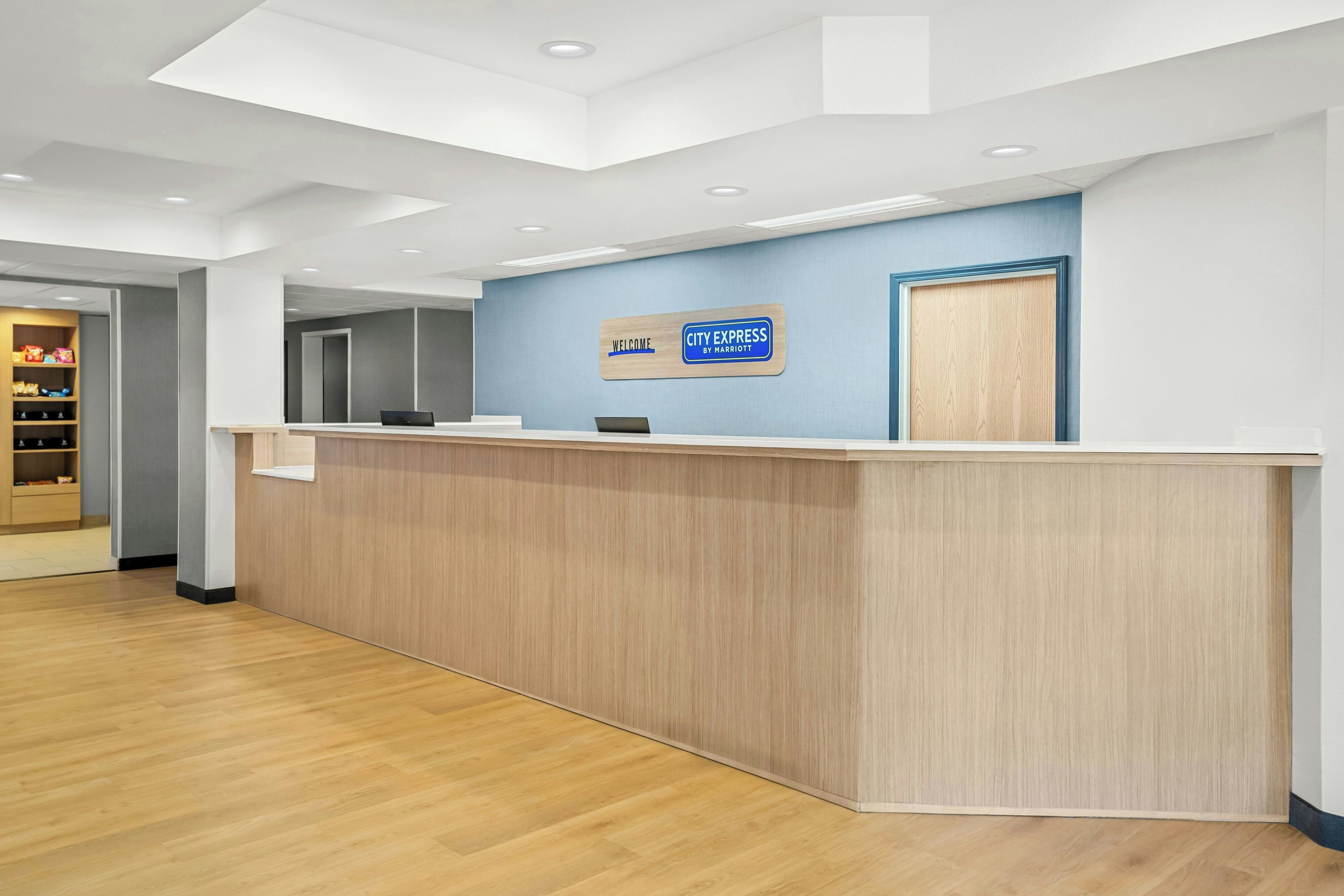A reception desk with a blue wall and a sign that reads 'Welcome City Express by Marriott.'