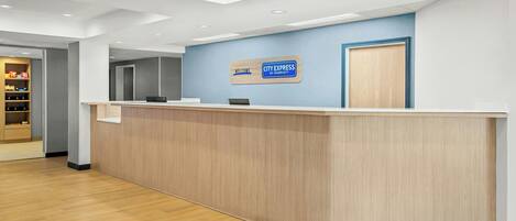 A reception desk with a blue wall and a sign that reads 'Welcome City Express by Marriott.'